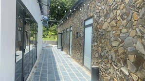 A corridor with stone walls, a tiled floor, and string lights. - Quiri Peninsula Hostel (Ha Giang 1)