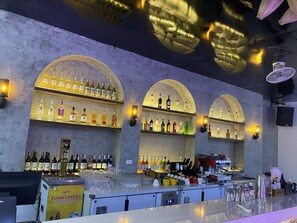 A bar area with multiple shelves of liquor bottles, a bar counter with glasses and a coffee machine, and a sign for NPP TUAN CHIVAS. - Quiri Peninsula Hostel (Ha Giang 1)