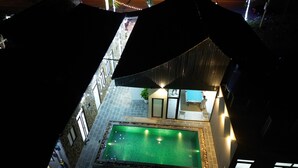 A rooftop swimming pool with a stone border, surrounded by a stone wall and a glass enclosure. - Quiri Peninsula Hostel (Ha Giang 1)