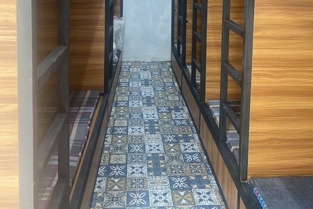 A narrow hallway with bunk beds on either side, a tiled floor, and a ceiling light.