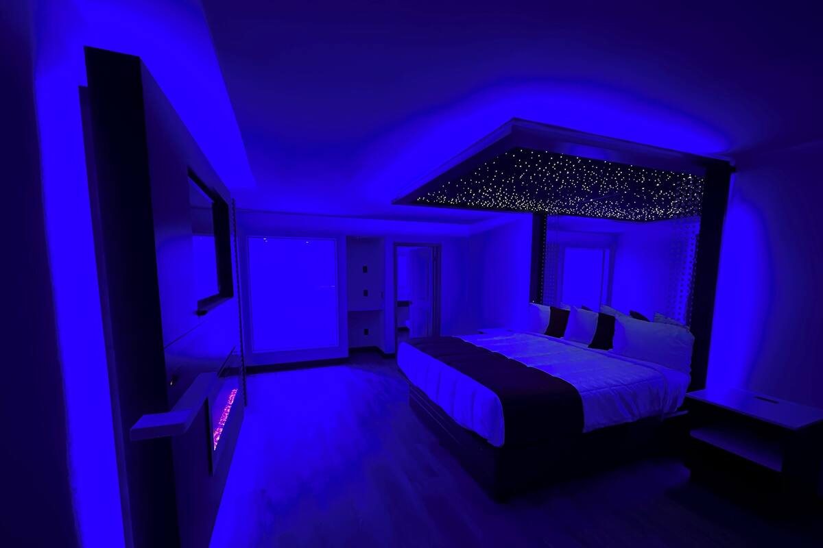 Une chambre moderne avec un grand lit, un luminaire au plafond et une table de chevet.