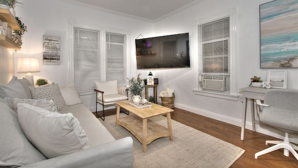 Un salon avec un canapé, une table basse et un téléviseur fixé au mur.