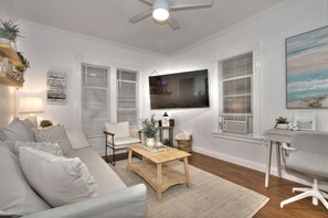 Un salon avec un canapé, une table basse et un téléviseur fixé au mur.