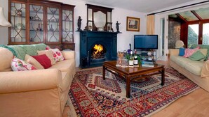 A living room with a fireplace, two sofas, a coffee table, and a television. - Slade Cottage (Bridgend)