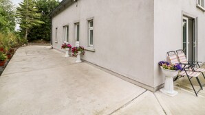 A building with a concrete exterior, multiple windows, and outdoor seating with chairs and tables. - Ahiohill Meadows (Aghyoghil Beg)