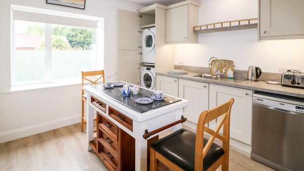 A compact kitchen with a dining area, built-in appliances, and a view through a window. - Ahiohill Meadows (Aghyoghil Beg)
