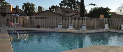 Une piscine avec des chaises longues et une clôture.