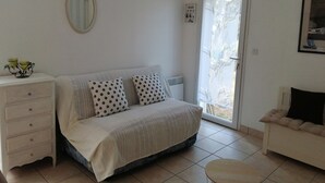 A bedroom with a bed, a bedside table, a chair, a window, and a door. - Maison Proximitée Plage de Banastère 2 Personnes (Sarzeau)