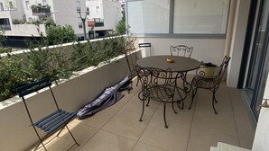 Un balcón con una mesa y sillas, un banco y una zona cubierta.