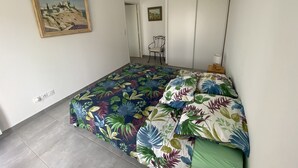 Un dormitorio con cama, una silla, un armario y un cuadro en la pared.