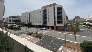 Un edificio moderno de varios pisos con balcones, un paso de peatones y una señal de parada.