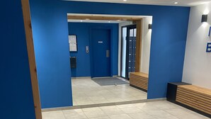 Un vestíbulo amplio con paredes azules, piso de baldosas y un banco de madera.
