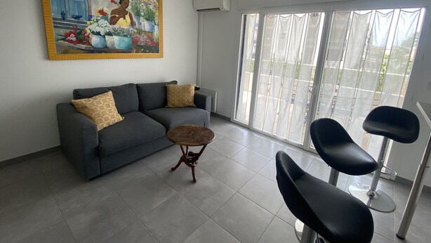 Una sala de estar con un sofá gris, dos sillas negras, una mesita de centro de madera y un cuadro grande en la pared.