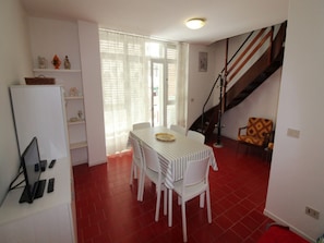 A compact living space with a dining area, a staircase, and a white refrigerator.