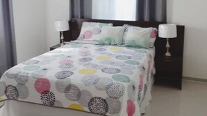 A bedroom with a bed, two bedside lamps, a ceiling fan, and a window with curtains. - Cozy updated family sized Condo just Minutes from Ocho Rios (Tower Isle)
