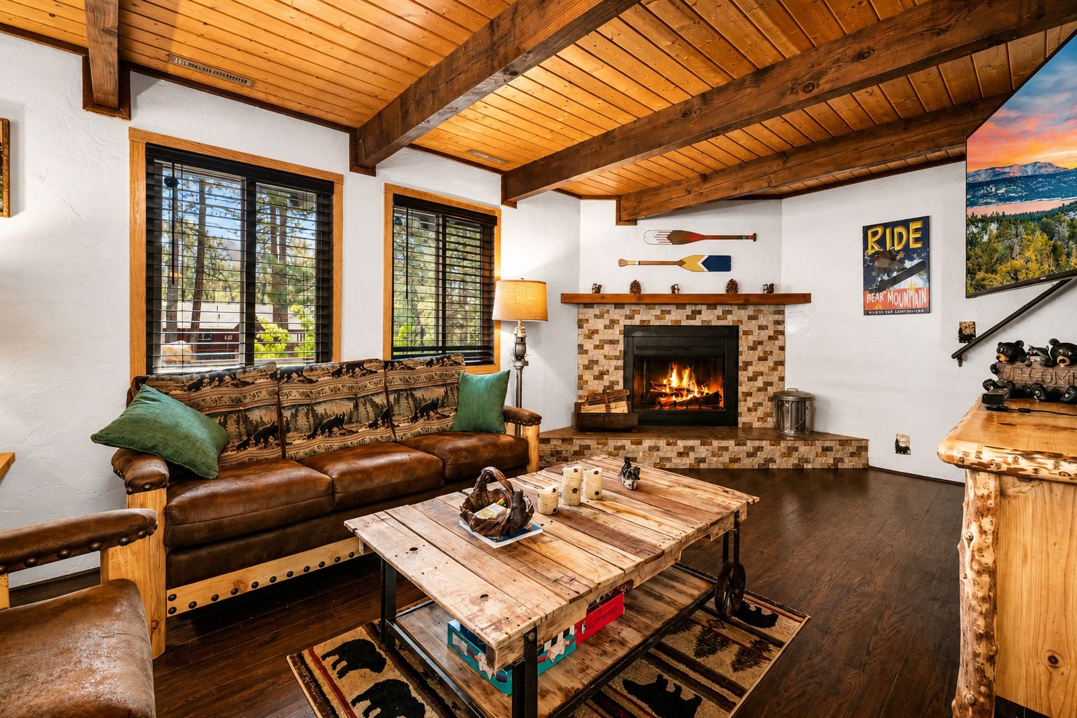 A cozy living room with a fireplace, wooden furniture, and a scenic view.