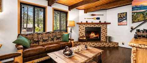 A cozy living room with a fireplace, wooden furniture, and a scenic view.