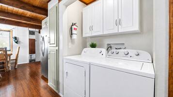 A laundry area with a washing machine, dryer, and a fire extinguisher on the wall.