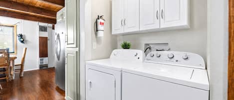 A laundry area with a washing machine, dryer, and a fire extinguisher on the wall.