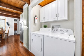 A laundry area with a washing machine, dryer, and a fire extinguisher on the wall.