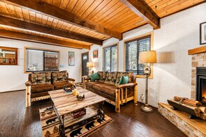 Ein gemütliches Wohnzimmer mit Holzmöbeln, einem Kamin und einem großen Fenster.
