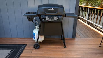 A Char-Broil grill on a wooden deck with a gas tank nearby.