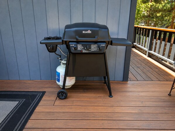 A Char-Broil grill on a wooden deck with a gas tank nearby.