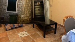 A room with a stone wall, a small table, a chair, and a television mounted on the wall. - Studio apartment in Sukošan with Air condition, WIFI (5102-2) (Sukošan)