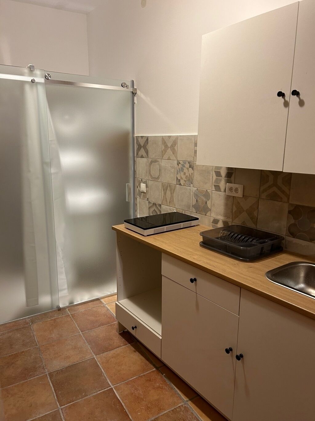 Eine kleine Küche mit Kühlschrank, Spüle und einer Arbeitsplatte mit Geschirrgestell.