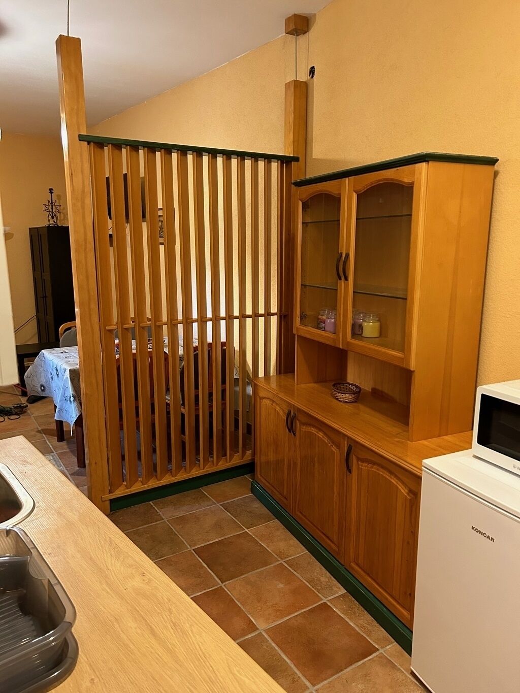 Cucina con mobili in legno, un forno a microonde e un'area pranzo con tavolo e sedie.