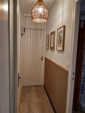 Un couloir avec une porte en bois, un radiateur et des tableaux encadrés accrochés au mur.