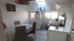 A compact kitchen with a dining area, a small refrigerator, and a window providing natural light.