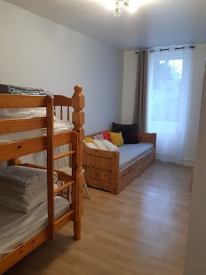 Una stanza con un letto a castello, un divano letto e una finestra con tende.
