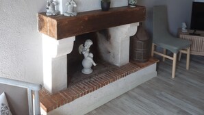 A fireplace with a mantel, a clock, and a framed picture on the wall.