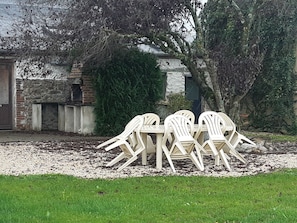 Un giardino con tavolo e sedie, circondato da un muro in mattoni e alberi.