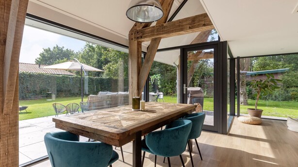 A dining area with a wooden table, teal chairs, and a hanging light fixture. - 6 persons - 2 badkamers (Ouddorp)