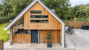 A modern wooden house with a sloped roof, large windows, and a small garden area. - 6 persons - 2 badkamers (Ouddorp)
