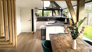 A modern kitchen with a large island, wooden beams, and a view of the outdoors. - 6 persons - 2 badkamers (Ouddorp)