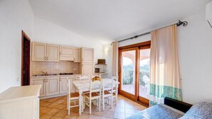 A compact room with a bed, a kitchenette, and a dining area.