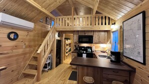 A wooden cabin interior with a kitchen area, wooden staircase, and a dining area. - Forest Getaway (Mountain City)