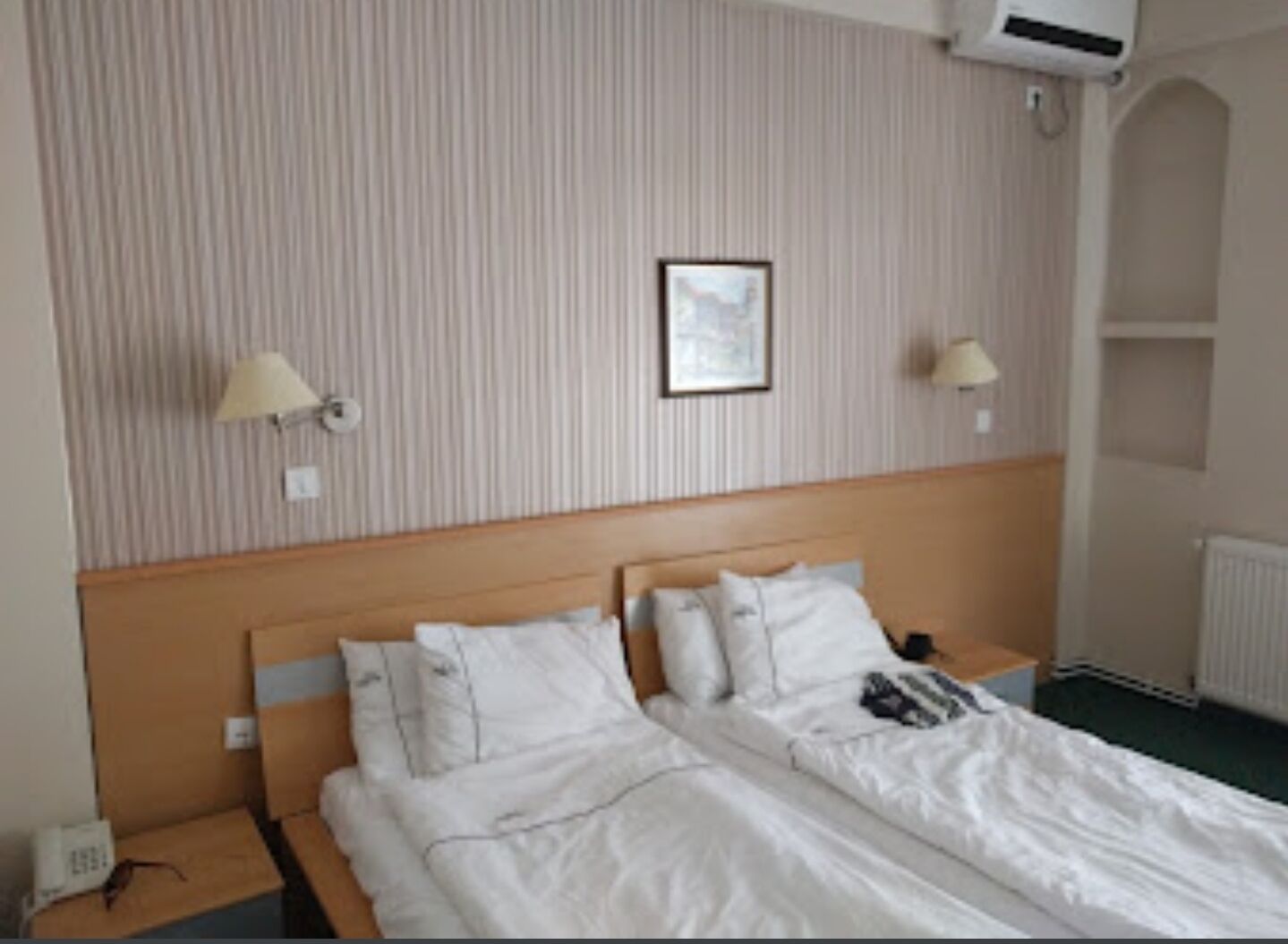 A hotel room with a large bed, two bedside tables, a headboard, and a framed picture on the wall.