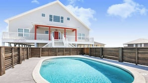 Une maison à deux étages avec une piscine en premier plan.
