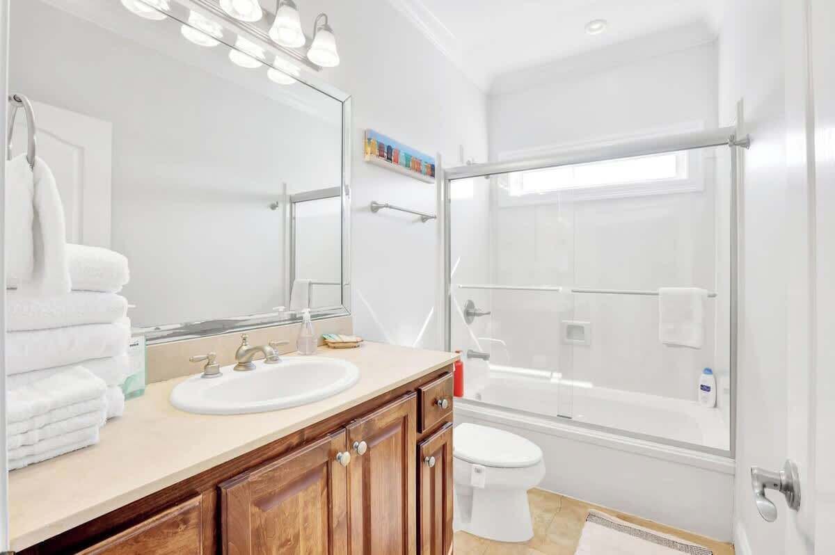 A bathroom with a sink, mirror, and shower.