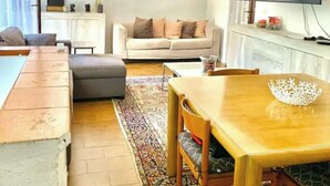 Una sala de estar moderna con sofá, mesa de comedor, televisor y ventilador de techo.