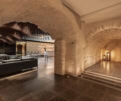 Un vestíbulo amplio con diseño moderno, que incluye un mostrador de recepción, una zona de estar y una escalera que conduce a pisos superiores.