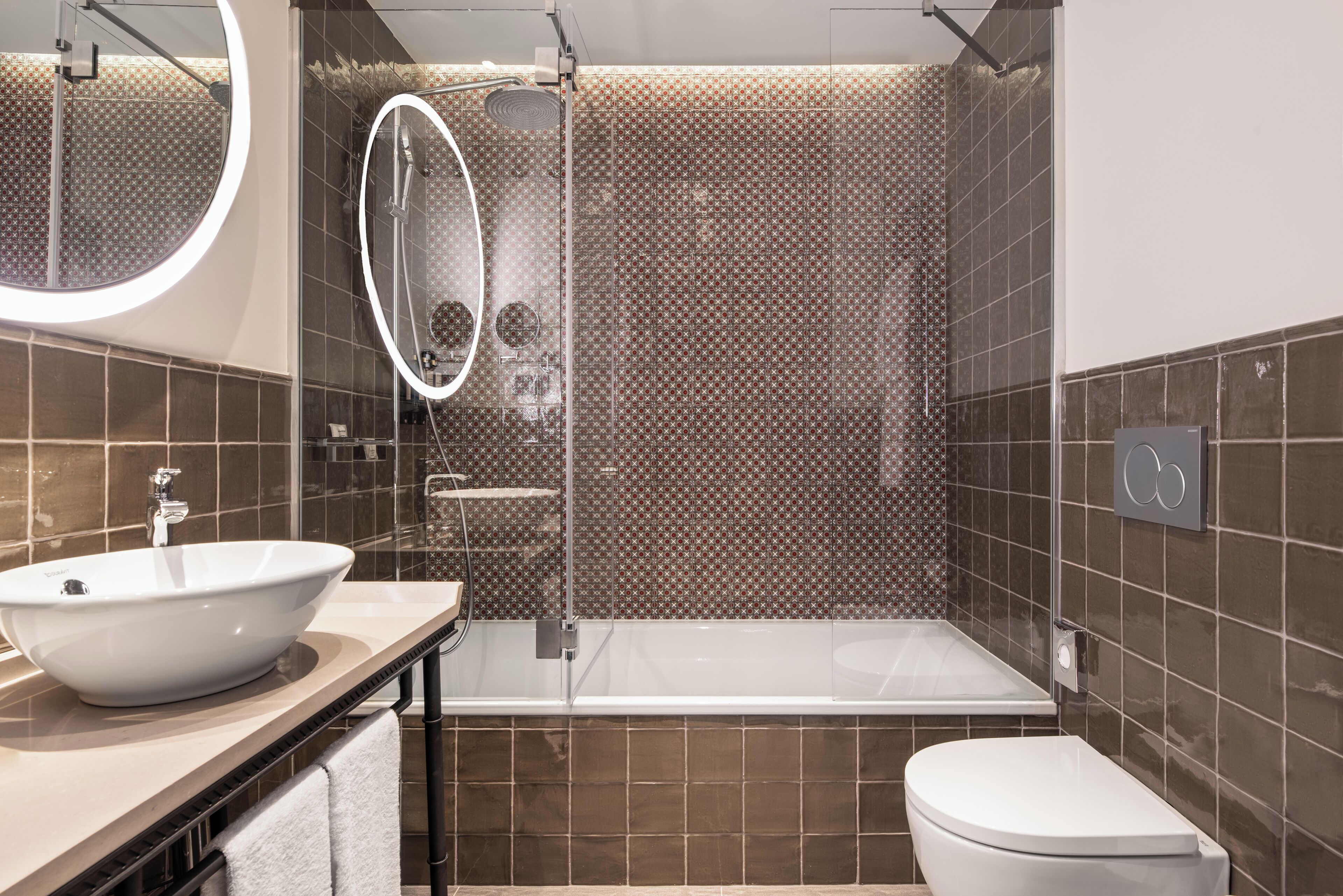 A modern bathroom with a large mirror, a bathtub, and a toilet.