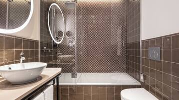 A modern bathroom with a large mirror, a bathtub, and a toilet.