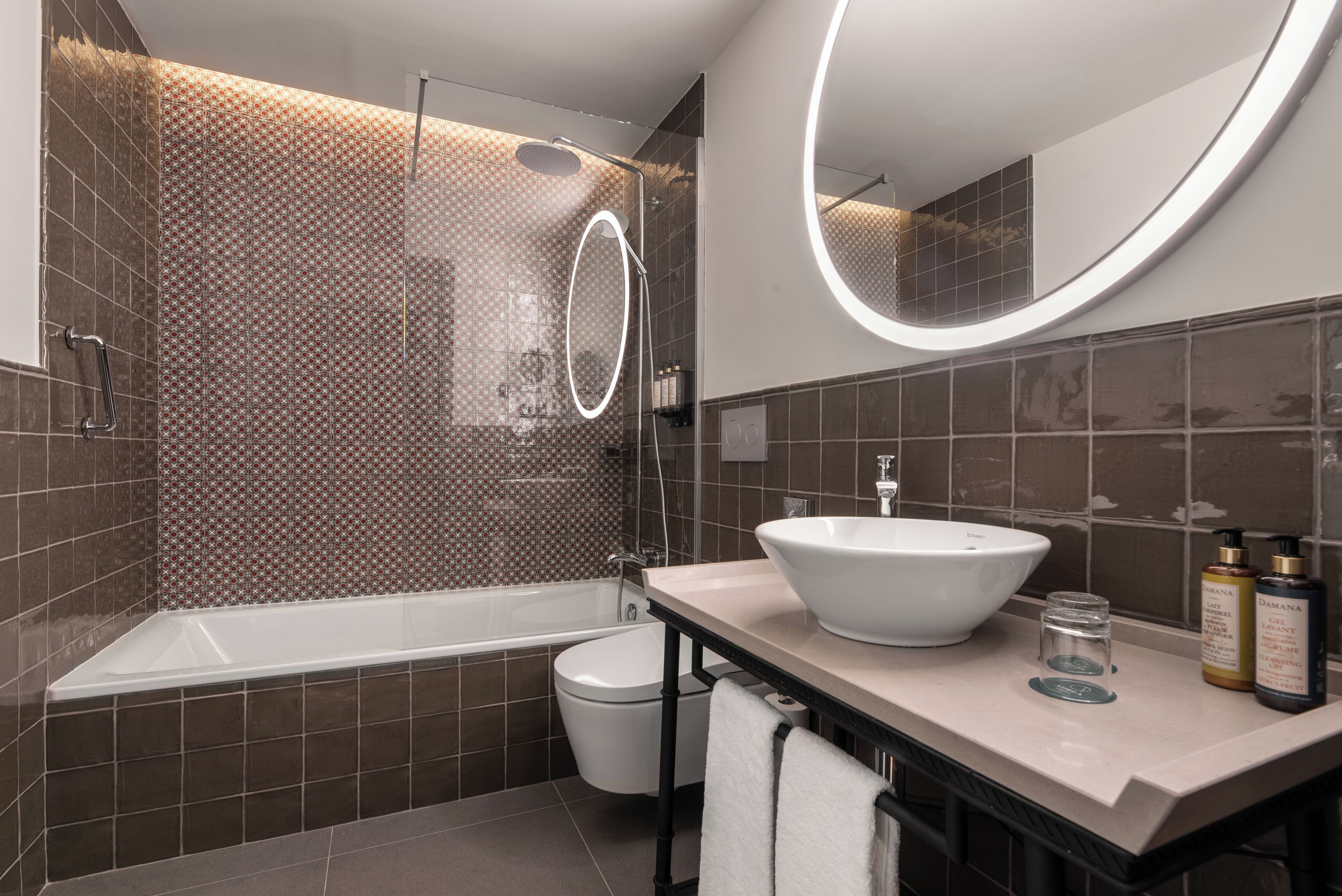 A modern bathroom with a bathtub, toilet, and vanity with a sink and mirror.