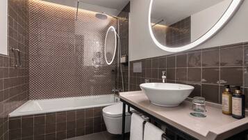 Un baño moderno con bañera, inodoro y tocador con lavamanos y espejo.