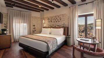 Habitación de hotel con cama, escritorio, silla, una mesita y vistas al exterior.